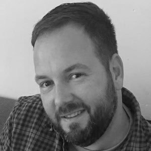 Professionele man met korte baard en glimlach, zakelijk portret voor bedrijfs- en ondernemersadvies, focus op zakelijk succes en groei.